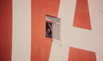 Movie still from “The Last Black Man in San Francisco” (2019), directed by Joe Talbot – A person looking out of an open window in a building; Extreme Wide shot, Low angle