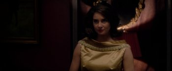 Movie still from “The Last Letter from Your Lover” (2021), directed by Augustine Frizzell – A woman in a yellow dress standing next to a wall; Close Up shot, Over the shoulder angle