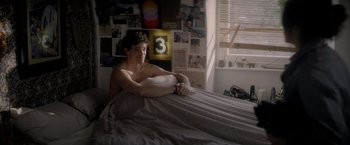 Movie still from “The Last Letter from Your Lover” (2021), directed by Augustine Frizzell – A man laying on a bed in a room; Medium shot, High angle