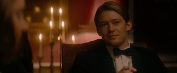 Movie still from “The Last Letter from Your Lover” (2021), directed by Augustine Frizzell – A man sitting in a chair wearing a tuxedo; Close Up shot, Over the shoulder angle