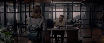 Movie still from “The Last Letter from Your Lover” (2021), directed by Augustine Frizzell – A man sitting at a desk in front of a laptop computer; Wide shot, Over the shoulder angle