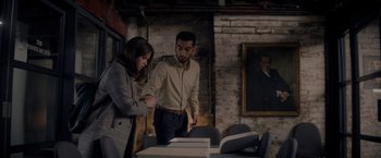 Movie still from “The Last Letter from Your Lover” (2021), directed by Augustine Frizzell – A man and a woman standing in front of a table; Medium shot, Over the shoulder angle