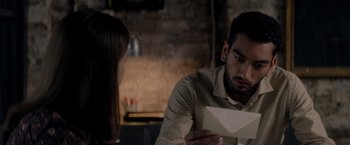 Movie still from “The Last Letter from Your Lover” (2021), directed by Augustine Frizzell – A man and a woman sitting at a table holding an open envelope; Close Up shot, Over the shoulder angle