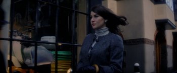 Movie still from “The Last Letter from Your Lover” (2021), directed by Augustine Frizzell – A beautiful woman in a gray coat standing next to a railing; Close Up shot, Over the shoulder angle