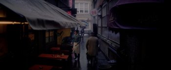 Movie still from “The Last Letter from Your Lover” (2021), directed by Augustine Frizzell – People walking down a street in the rain; Wide shot, High angle