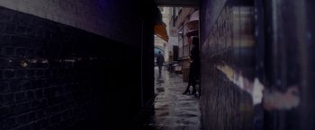 Movie still from “The Last Letter from Your Lover” (2021), directed by Augustine Frizzell – Two people walking down a wet street in the dark; Extreme Wide shot, High angle