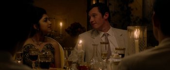 Movie still from “The Last Letter from Your Lover” (2021), directed by Augustine Frizzell – A man and a woman sitting at a dinner table; Medium shot, Over the shoulder angle