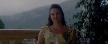 Movie still from “The Last Letter from Your Lover” (2021), directed by Augustine Frizzell – A woman sitting at a table with a glass of water; Close Up shot, Over the shoulder angle