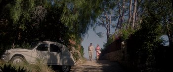 Movie still from “The Last Letter from Your Lover” (2021), directed by Augustine Frizzell – A man and a woman walking down a street; Extreme Wide shot, High angle