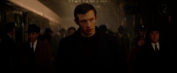 Movie still from “The Last Letter from Your Lover” (2021), directed by Augustine Frizzell – A man standing in the middle of a crowd of people; Close Up shot, Over the shoulder angle