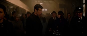 Movie still from “The Last Letter from Your Lover” (2021), directed by Augustine Frizzell – A crowd of people standing in a room; Medium shot, Over the shoulder angle