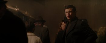 Movie still from “The Last Letter from Your Lover” (2021), directed by Augustine Frizzell – A group of people standing in a room; Medium shot, Over the shoulder angle