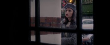 Movie still from “The Last Letter from Your Lover” (2021), directed by Augustine Frizzell – A woman wearing a hat looking out of a window; Close Up shot, Over the shoulder angle