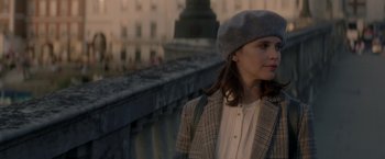 Movie still from “The Last Letter from Your Lover” (2021), directed by Augustine Frizzell – A woman wearing a hat and a jacket standing on a bridge; Close Up shot, Over the shoulder angle