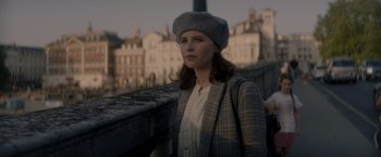 Movie still from “The Last Letter from Your Lover” (2021), directed by Augustine Frizzell – A woman wearing a hat standing on a bridge; Close Up shot, Over the shoulder angle