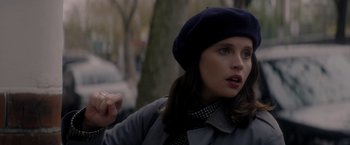 Movie still from “The Last Letter from Your Lover” (2021), directed by Augustine Frizzell – A young woman wearing a blue hat and a scarf; Close Up shot, Over the shoulder angle