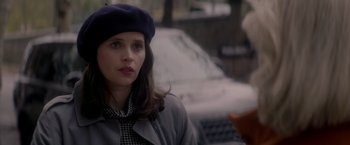 Movie still from “The Last Letter from Your Lover” (2021), directed by Augustine Frizzell – A woman wearing a hat and a coat; Close Up shot, Over the shoulder angle