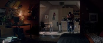 Movie still from “The Last Letter from Your Lover” (2021), directed by Augustine Frizzell – A person sitting at a table in a room; Extreme Wide shot, Over the shoulder angle