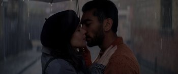 Movie still from “The Last Letter from Your Lover” (2021), directed by Augustine Frizzell – A man and a woman kissing in the rain under an umbrella; Close Up shot, Overhead angle