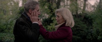 Movie still from “The Last Letter from Your Lover” (2021), directed by Augustine Frizzell – An older man and a younger woman touching each other's ear; Close Up shot, Over the shoulder angle