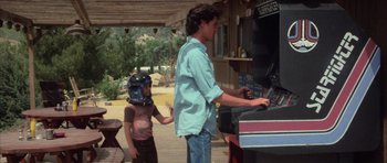 Movie still from “The Last Starfighter” (1984), directed by Nick Castle – A man and a little girl standing in front of an outdoor grill; Medium shot, Over the shoulder angle