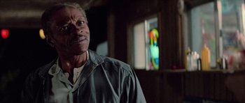 Movie still from “The Last Starfighter” (1984), directed by Nick Castle – An older man standing in front of a stained glass window; Close Up shot, Over the shoulder angle