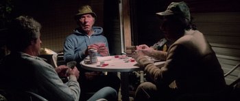 Movie still from “The Last Starfighter” (1984), directed by Nick Castle – A group of people sitting around a table playing cards; Medium shot, High angle