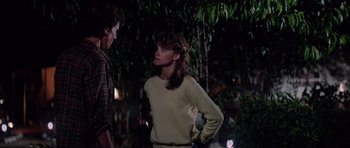 Movie still from “The Last Starfighter” (1984), directed by Nick Castle – A man and a woman standing next to each other in the dark; Medium shot, Over the shoulder angle