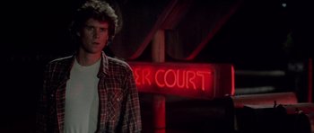 Movie still from “The Last Starfighter” (1984), directed by Nick Castle – A man standing in front of a red neon sign; Medium shot, Low angle