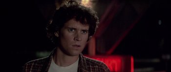 Movie still from “The Last Starfighter” (1984), directed by Nick Castle – A man with a beard is looking at the camera; Close Up shot, Over the shoulder angle