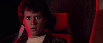 Movie still from “The Last Starfighter” (1984), directed by Nick Castle – A man sitting on a red chair in a dark room; Close Up shot, Low angle