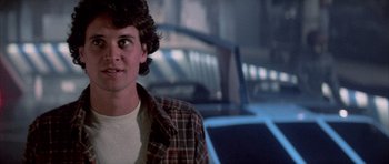 Movie still from “The Last Starfighter” (1984), directed by Nick Castle – A young man in a plaid shirt is looking at the camera; Close Up shot, Over the shoulder angle