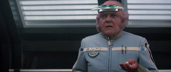 Movie still from “The Last Starfighter” (1984), directed by Nick Castle – An older man wearing a blue jacket and a red hat; Close Up shot, Over the shoulder angle