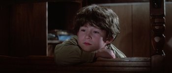 Movie still from “The Last Starfighter” (1984), directed by Nick Castle – A young boy sitting in a chair with his head resting on his arm; Close Up shot, Low angle