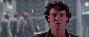 Movie still from “The Last Starfighter” (1984), directed by Nick Castle – A young man with curly brown hair stares into the camera; Close Up shot, Over the shoulder angle