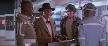 Movie still from “The Last Starfighter” (1984), directed by Nick Castle – An older man in a hat and a tie is using a computer; Medium shot, Over the shoulder angle