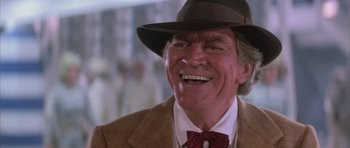 Movie still from “The Last Starfighter” (1984), directed by Nick Castle – An older man wearing a suit and a hat; Close Up shot, Over the shoulder angle