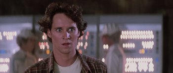 Movie still from “The Last Starfighter” (1984), directed by Nick Castle – A young man with curly brown hair wearing a checkered shirt; Close Up shot, Over the shoulder angle