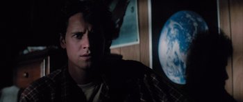 Movie still from “The Last Starfighter” (1984), directed by Nick Castle – A young man stares into the distance in front of the earth; Close Up shot, Low angle