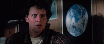 Movie still from “The Last Starfighter” (1984), directed by Nick Castle – A young man in a plaid shirt is looking surprised; Close Up shot, Low angle