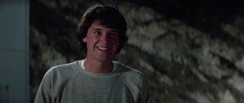 Movie still from “The Last Starfighter” (1984), directed by Nick Castle – A young man smiling for the camera in front of trees; Close Up shot, Low angle
