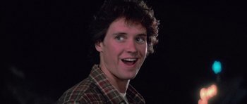 Movie still from “The Last Starfighter” (1984), directed by Nick Castle – A young man with curly brown hair wearing a plaid shirt; Close Up shot, Low angle