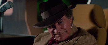 Movie still from “The Last Starfighter” (1984), directed by Nick Castle – An older man wearing a brown hat and a brown jacket; Close Up shot, Over the shoulder angle