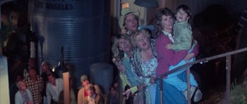 Movie still from “The Last Starfighter” (1984), directed by Nick Castle – A group of people standing next to each other on a stage; Medium shot, High angle