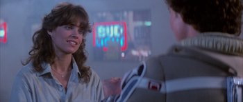 Movie still from “The Last Starfighter” (1984), directed by Nick Castle – A woman sitting next to a man in front of a neon sign; Close Up shot, Over the shoulder angle