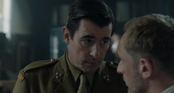 Movie still from “The Last Vermeer” (2019), directed by Dan Friedkin – A person wearing a military uniform; Close Up shot, Over the shoulder angle