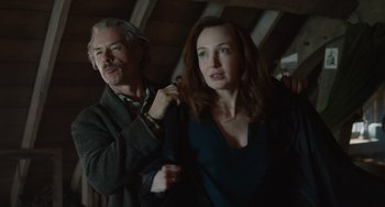 Movie still from “The Last Vermeer” (2019), directed by Dan Friedkin – An older man and a younger woman in a dark room; Medium shot, Low angle