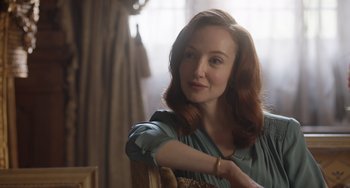 Movie still from “The Last Vermeer” (2019), directed by Dan Friedkin – A woman with red hair sitting in a chair in front of a window; Close Up shot, Over the shoulder angle