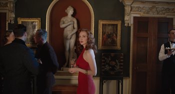 Movie still from “The Last Vermeer” (2019), directed by Dan Friedkin – A woman in a red dress holding a glass of wine; Medium shot, Over the shoulder angle