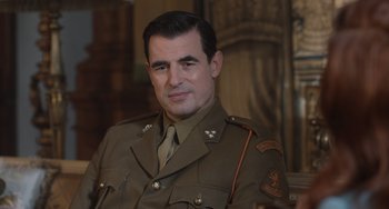 Movie still from “The Last Vermeer” (2019), directed by Dan Friedkin – A man in a military uniform is posing for a picture; Close Up shot, Over the shoulder angle